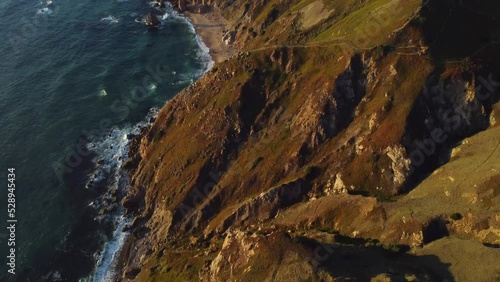 Wild impregnable rocky coastline of Portugal, Lisbon area. Aerial view at scenic huge cliffs with waving Atlantic ocean in the foot, breathtaking view of westernmost point of Europe - Cape Roca photo