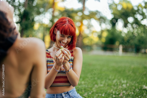 Funny red haired girl, sticking her tongue out, making funny faces, holding flowers.