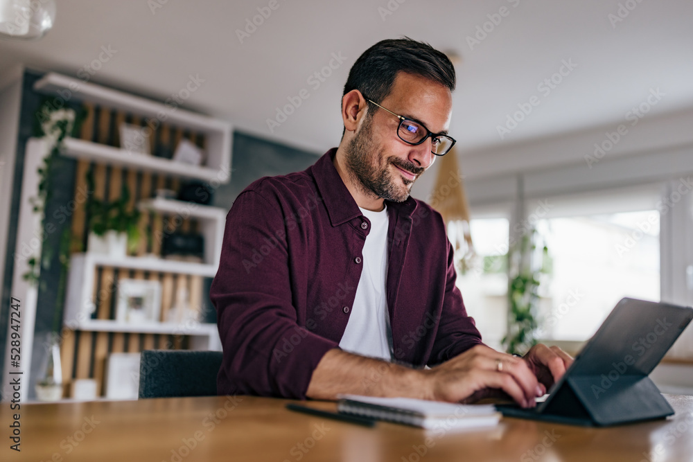 Obraz premium Adult man working over the tablet, typing something on the keyboard.
