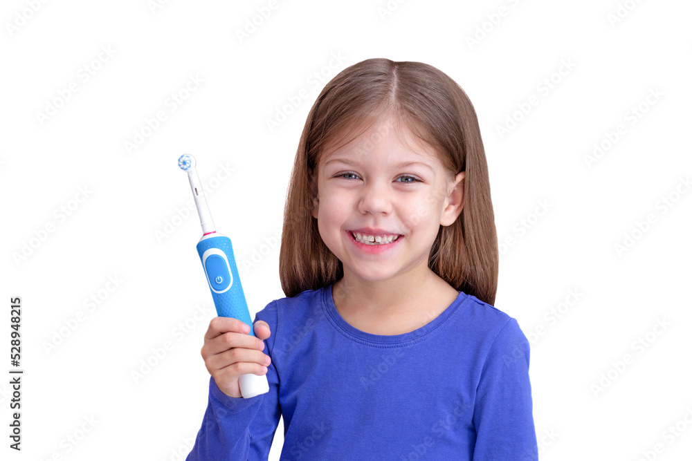 Smiling child holding electric toothbrush, isolated on white background looking at camera waist up caucasian little girl of 5 years in blue Smiling child holding electric toothbrush, isolated on white background looking at camera waist up caucasian little girl of 5 years in blue
