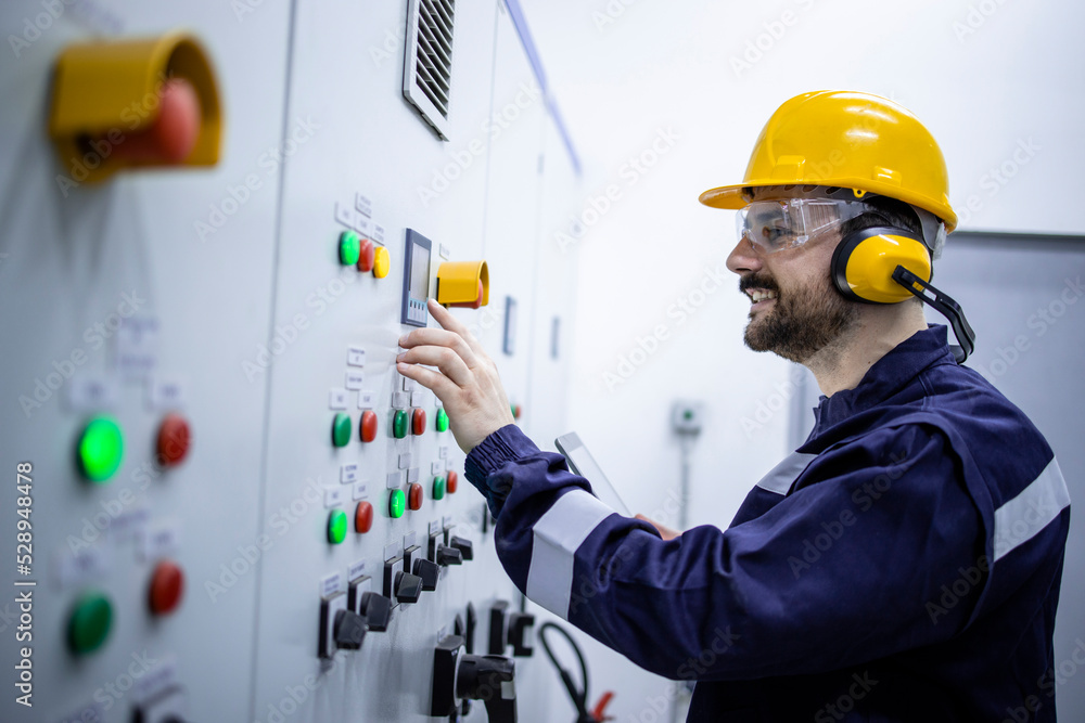 Professional electrical engineer standing by electric cabinet and checking installations. Professional electrical engineer standing by electric cabinet and checking installations.