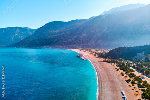 Aerial view of mediterranean sea bay with mountain, sandy beach and boats at sunny day in summer. Drone photo of Blue lagoon in Oludeniz, Turkey