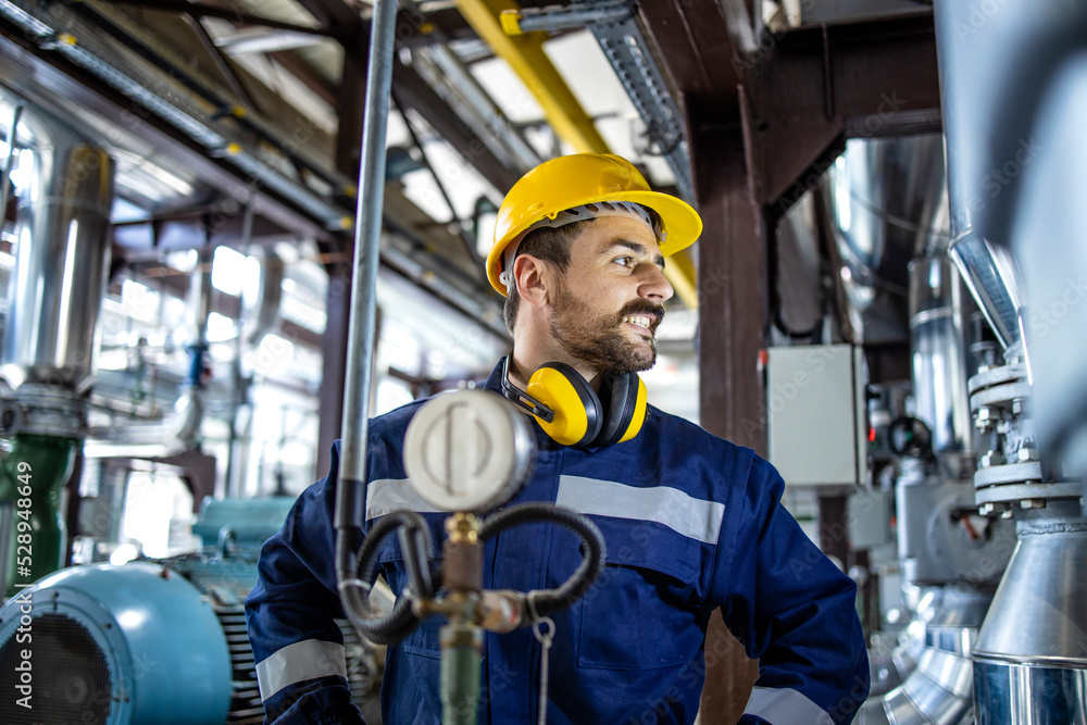 Blue collar worker in hardhat standing in power plant producing electricity. Blue collar worker in hardhat standing in power plant producing electricity.