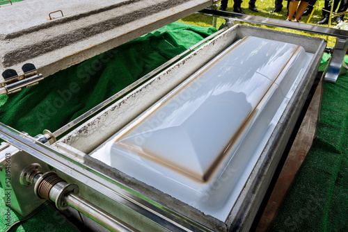 An automatic elevator is used to lower the coffin into a grave by means of funeral service in a cemetery photo