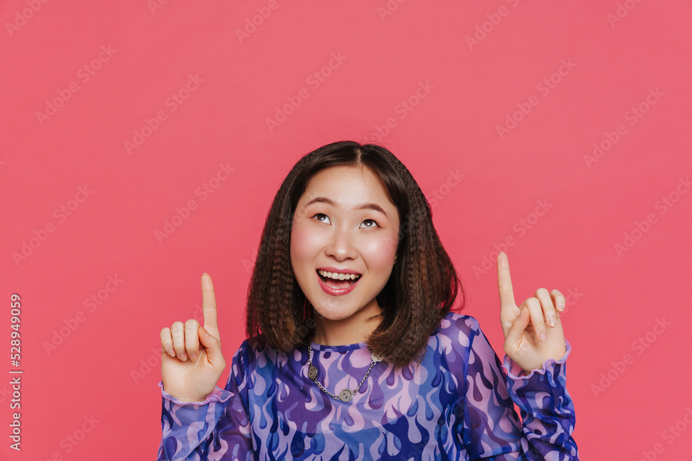 Young cute happy asian girl looking and pointing upward Young cute happy asian girl looking and pointing upward