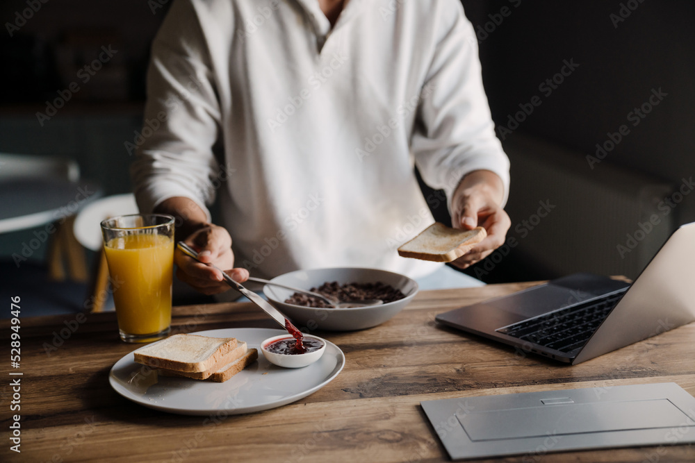 Blonde bristle man having breakfast while working with laptop at home Blonde bristle man having breakfast while working with laptop at home