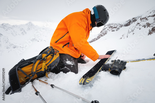Canvastavla Ski tourist repairs skis in snowy mountains