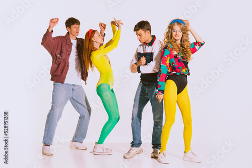 Group of stylish people, boys and girls in bright retro outfits dancing at the disco, party isolated over grey background