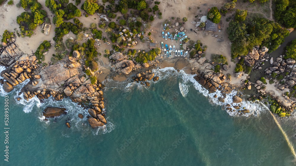 Ocean tropical landscape, rocky coast with fishing boats, drone shot, water and beach.