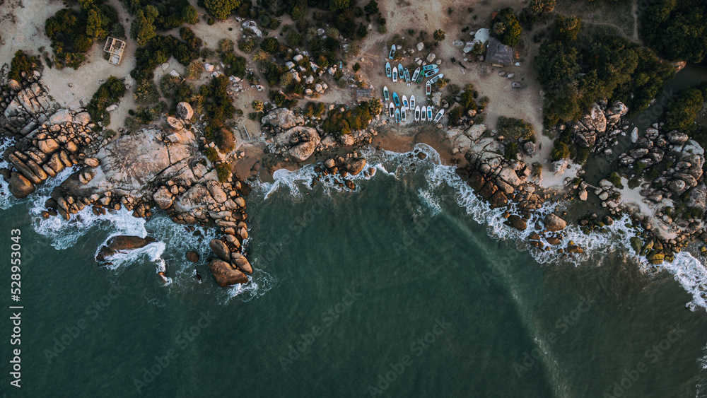 Ocean tropical landscape, rocky coast with fishing boats, drone shot, water and beach.