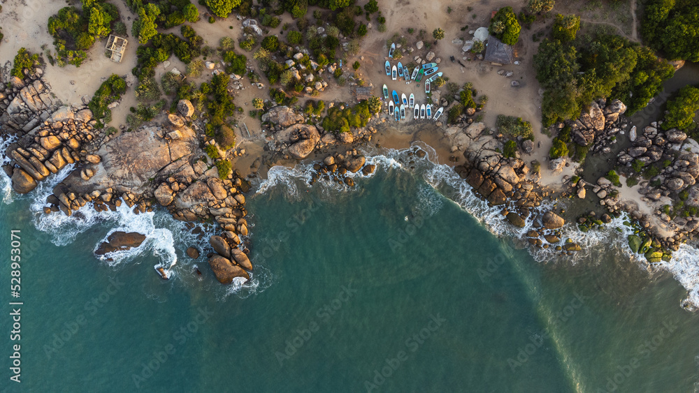 Ocean tropical landscape, rocky coast with fishing boats, drone shot, water and beach.
