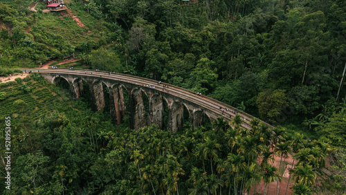 9 Arch Railway Bridge, Ella in Sri Lanka, a historic building set against a green tropical jungle background.