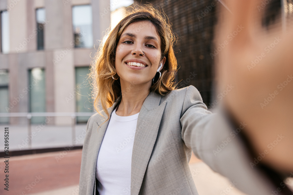 Fototapeta premium Pretty young caucasian girl posing looking at camera standing outdoors during day. Brown-haired model wears grey jacket on casual day. Independent woman concept