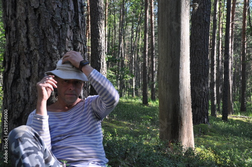 a man in the forest, hiking, on the grass around blueberries, a cocked hat and a blue vest © Евген Кузнецов
