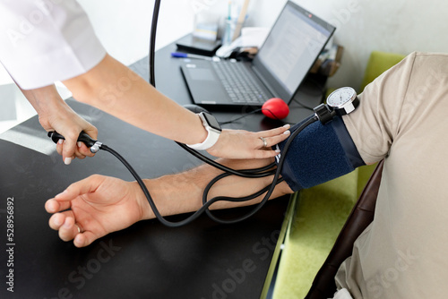 Woman doctor measures by tonometer blood pressure for patient in clinic.