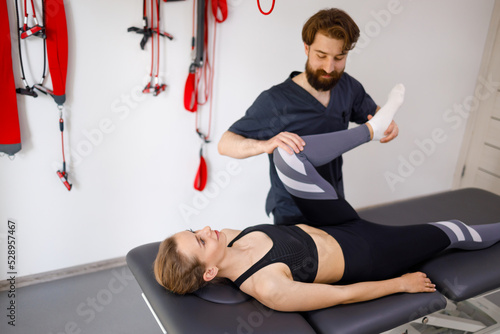 Physiotherapist working with legs of young female patient in rehabilitation center