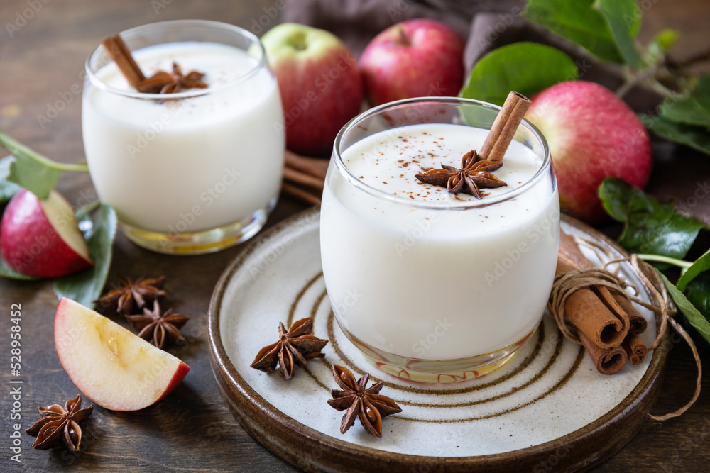 Homemade banana apple smoothie with apples, yogurt, cinnamon, spices or lassi in a glass on a rustic table. Homemade banana apple smoothie with apples, yogurt, cinnamon, spices or lassi in a glass on a rustic table.