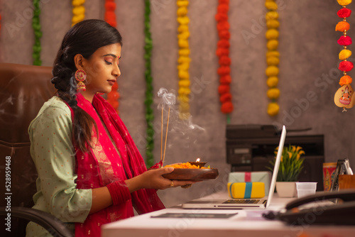 Female employee praying to Godduring Diwali celebration photo