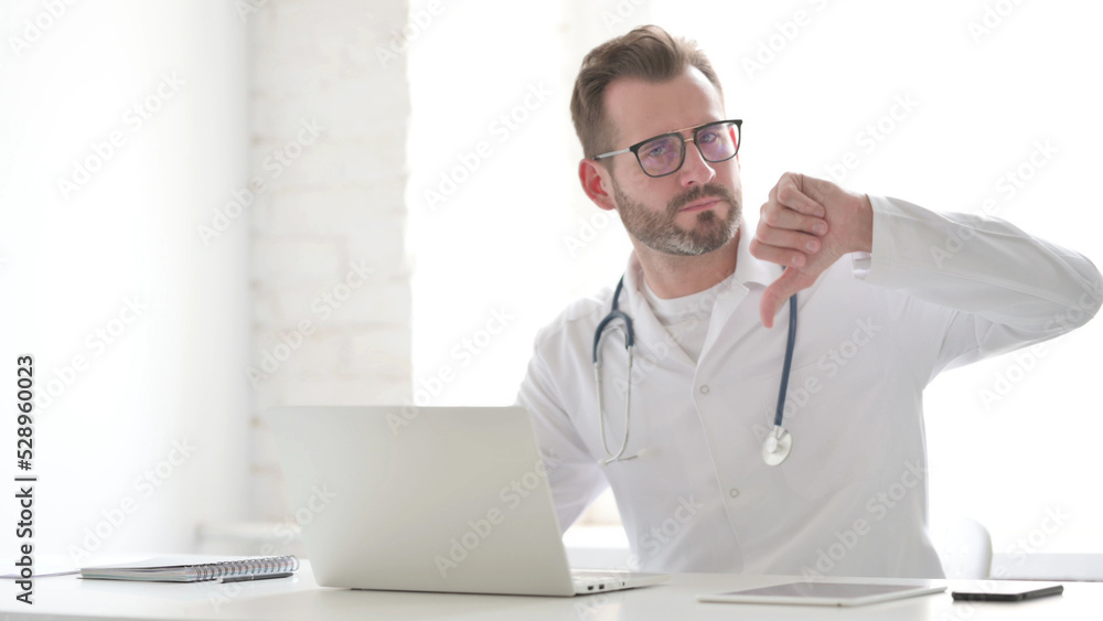 Doctor Showing Thumbs Down Sign While using Laptop in Clinic Doctor Showing Thumbs Down Sign While using Laptop in Clinic