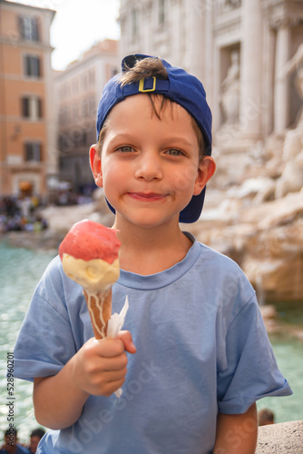 Photography Cute cheerful boy 7 years old eating ice cream (gelato) near the Trevi Fountain in Rome, Italy