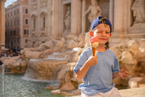 Cute cheerful boy 7 years old eating ice cream (gelato) near the Trevi Fountain in Rome, Italy.