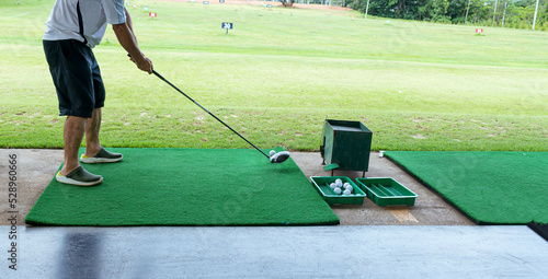 Man practicing hitting a golf ball and swinging on a driving range
