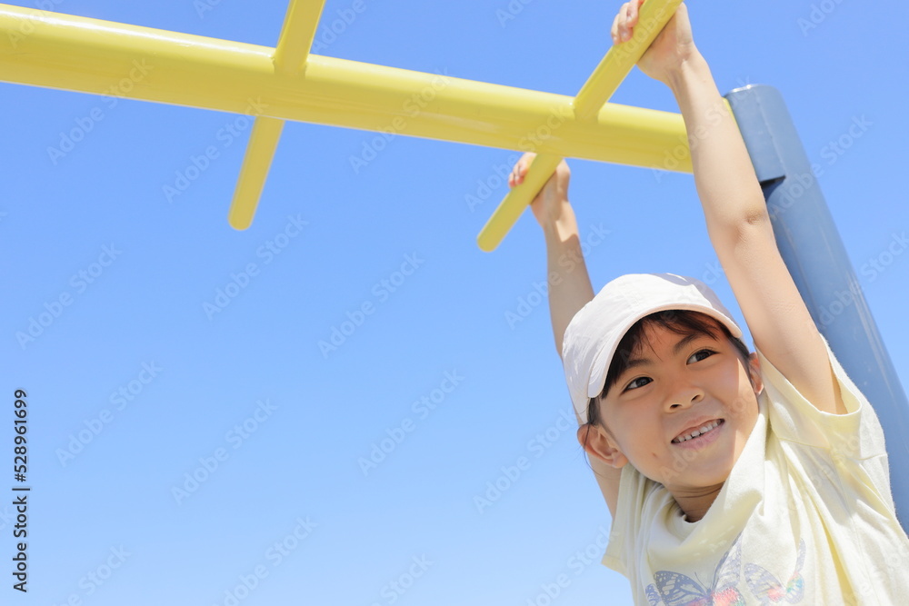 Fototapeta premium 雲梯で遊ぶ女子小学生 (7歳)