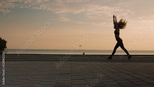 Young woman doing backflips.Girl doing acrobatic activity against the sea at sunrise. Fitness Lifestyle slow motion