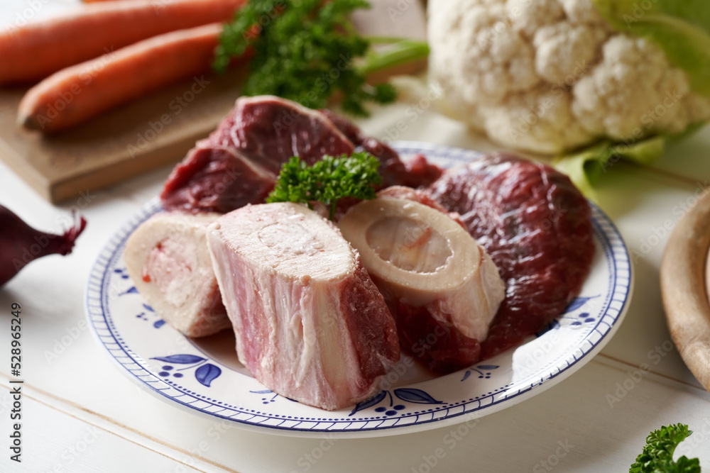 Marrow bones, meat and vegetables - ingredients for preparing beef bone broth or soup