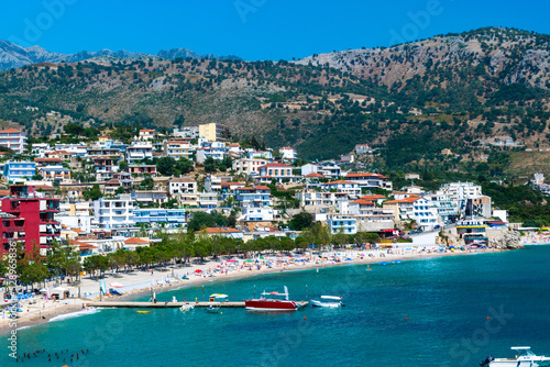 Fototapeta Naklejka Na Ścianę i Meble -  Beautiful summer cloud landscape of beach town of Himare at foot of  mountains on border of Ionian and Adriatic seas. Albania.