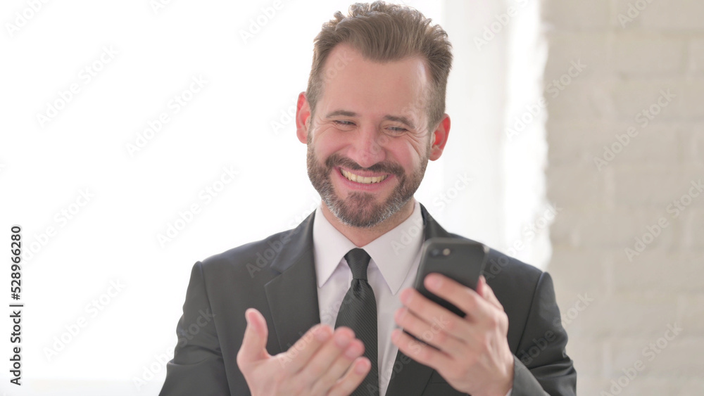 Young Businessman Celebrating Success on Smartphone Young Businessman Celebrating Success on Smartphone