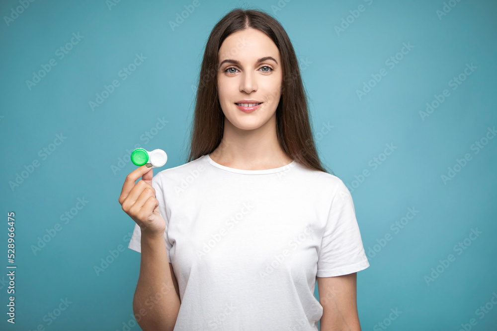 Young woman holding contact lenses looking positive and happy standing and smiling with a confident smile showing teeth Young woman holding contact lenses looking positive and happy standing and smiling with a confident smile showing teeth