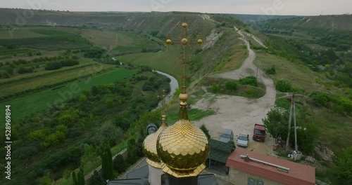 aerial orbit footage of golden dome with cross on church from old orhei, orheiul vechi, moldova photo