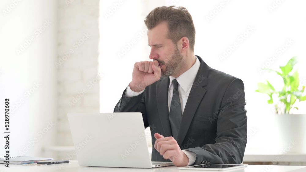 Young Businessman Coughing while using Laptop in Office