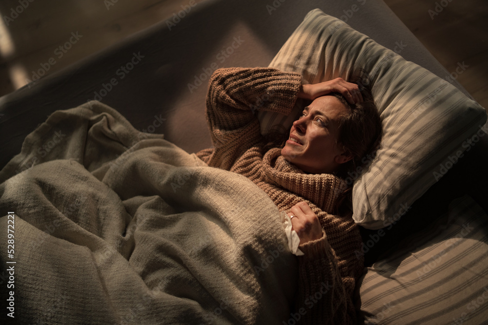 Sad mature woman suffering from depression lying alone in bed in night. Sad mature woman suffering from depression lying alone in bed in night.