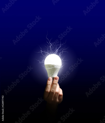 In one hand holding a bright lamp, lightning flashed from the lamp against a dark blue background. new idea ideas Energy saving, bright future