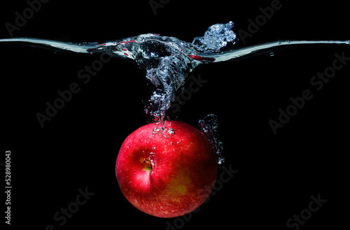 Fresh apple dropped in water with splashes on black