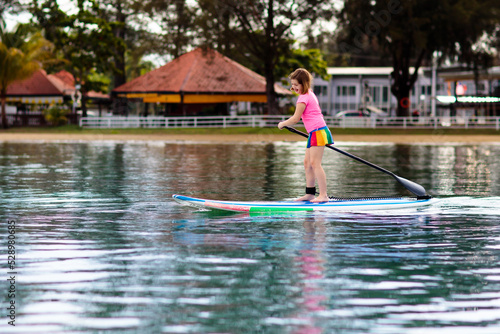 Fototapeta Naklejka Na Ścianę i Meble -  Child on stand up paddle. Water and beach sport
