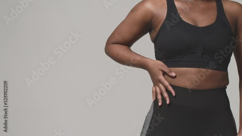 African american woman in sports clothes showing fat folds on waise, closeup, copyspace. Body positive, slimming. ProRes
