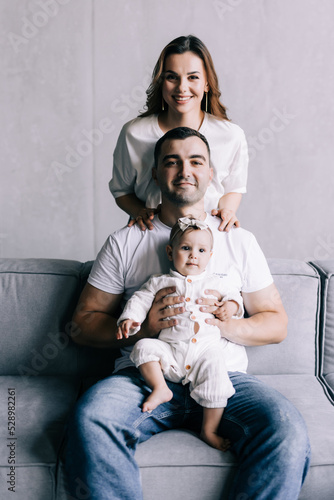 Happy family mother, father, child baby daughter at home on the sofa playing