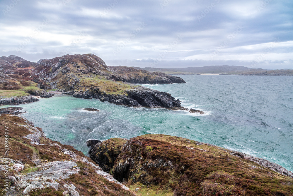 Rugged Scottish west highland coast with breaking aqua waves and heather covered rocks