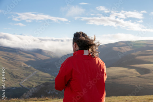male traveler on the background of the mountain looks into the distance. View from the back.