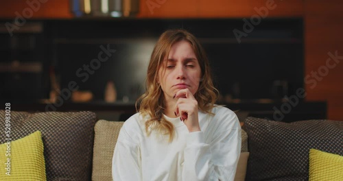 Pensive worried young caucasian woman watching soap opera, television series, sigh heavily, thinking, sitting on couch