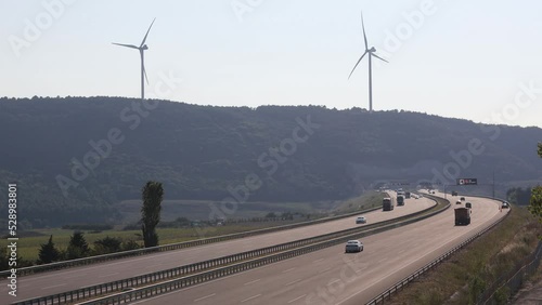 Istanbul, Turkiye - August 2022: Northern Marmara Motorway traffic is running on both east and west directions there are electric generator wind turbines on the top of the mountain in the background photo
