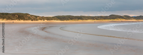 Breaking waves creating curves over the large beach in Dunnet Bay Scotland