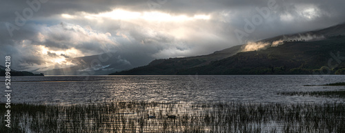 Morning sunbreak through clouds over loch Tay lake Scotland with mist on hills photo