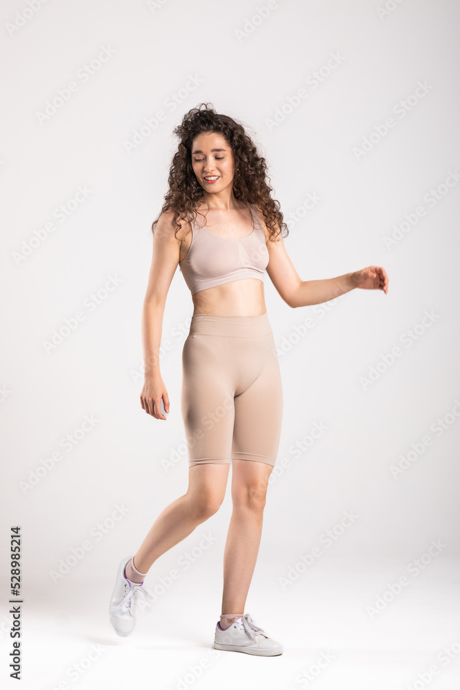 Fototapeta premium Sport woman in sportswear relax stand after workout against copy space for adding text with white wall background.Diet concept.Fitness and healthy lifestyle