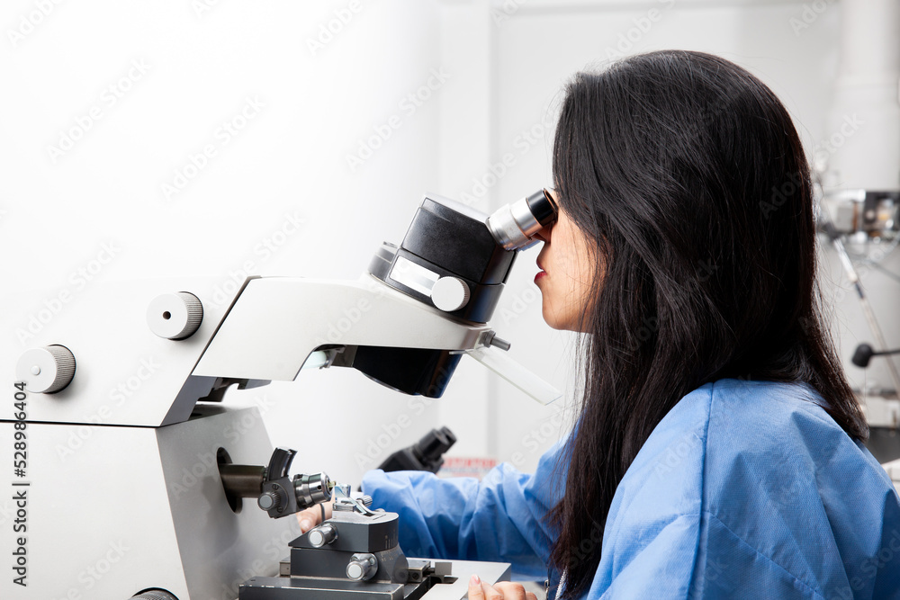 Fototapeta premium Young female scientist using an ultramicrotome to make sections for the electron microscope