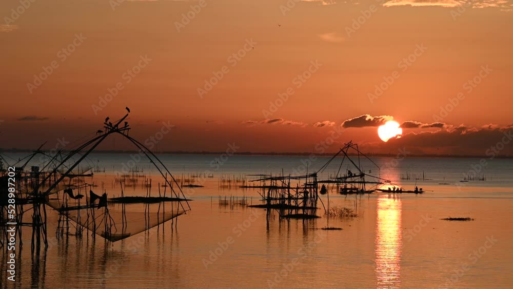 Square dip net in lake with sunrise at Pak pra village, Phatthalung, Thailand Square dip net in lake with sunrise at Pak pra village, Phatthalung, Thailand