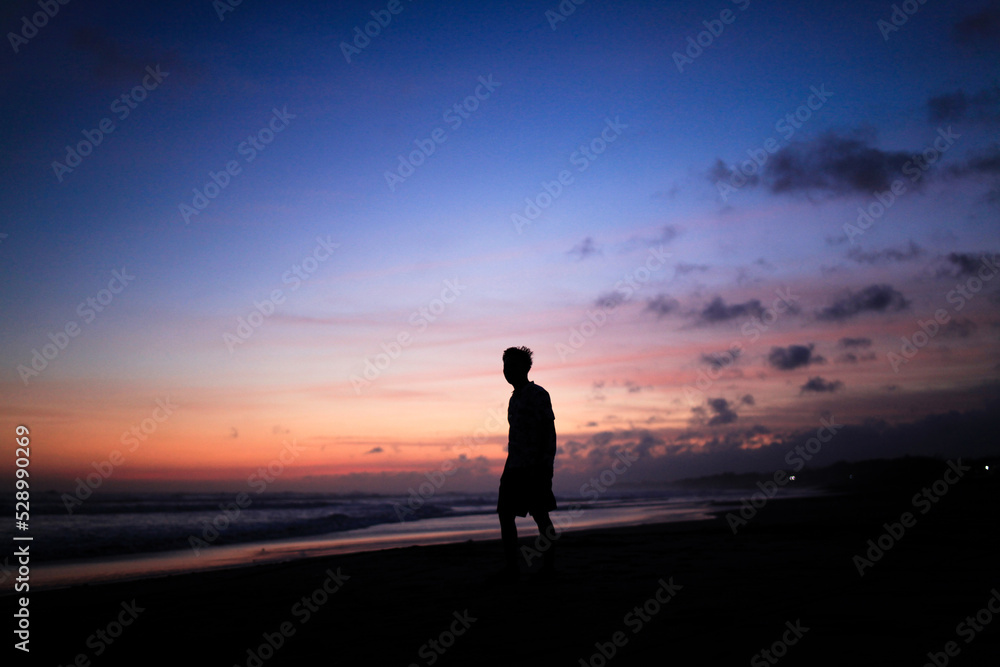 the silhouette of a man standing at the background of sunset